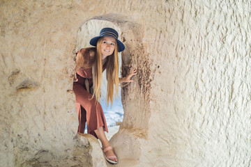 Young woman exploring valley with rock formations and fairy caves near Goreme in Cappadocia Turkey