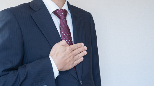 安心・おまかせポーズ｜スーツ姿で胸に手を当てる男性