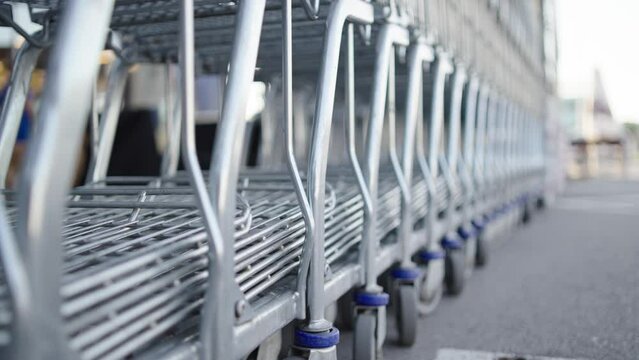 Row of shopping carts outside by store on parking lot.