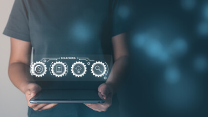 Searching and learning concept, businessman using smart device for connecting to internet of things (IOT), learning and entertainment, light bulb, virtual graphics, icons concept.