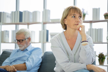 Sad mature woman sitting away from her husband after having quarrel