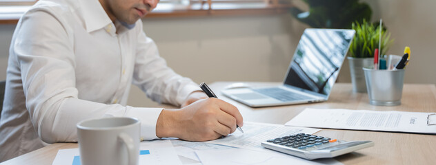 Close up hand of professional accountant review tax paperwork and signing signature on the table in workplace
