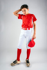 Male youth baseball player standing with hat in hand