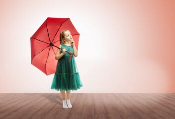 little girl thinks. cute little girl in green dress with umbrella on color background.