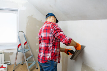 Professional worker plastering plasterboard wall. Wall repair. House renovation concept.