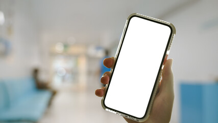 Hand holding mobile smart phone with blurred hospital corridor on background. Medical, healthcare and technology concept