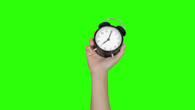 hand holding alarm clock green background