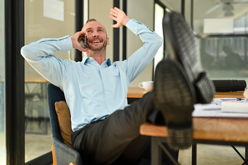 Fototapeta premium Happy caucasian millennial man chatting with friends distracted from work while relaxing at workplace