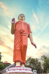 Fototapeta na wymiar The statue of a Buddhist monk in orange tones in a Buddhist temple in Sri Lanka