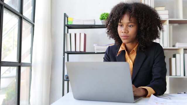 Serious african american businesswoman thinking while working with laptop on office desk. Stress and pressure concept from overwork.