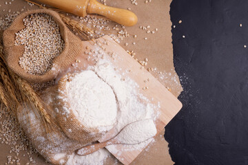 Flour and wheat grains in sacks with wheat ears On a black background table. In a rustic kitchen. Top view.