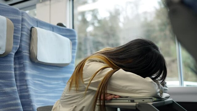 Asian woman napping after work on laptop computer during travel on railway transportation. Businesswoman working online corporate business outside office. Work from anywhere and digital nomad concept.