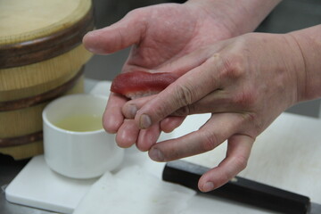 Fototapeta na wymiar Professional sushi chef hand preparing sashimi to make perfect sushi with precision and confidence.