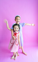Two pretty little girls standing while reaching out wide and laughing.