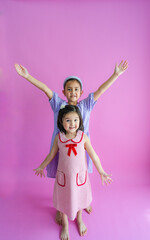 Two pretty little girls standing and reaching up high and low.