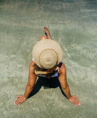 afro black woman in hat sitting on the beach enjoying the hot sun during summer vacation