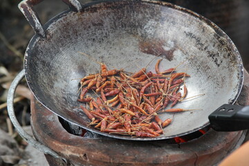 Roasted dry chilies in a pan. Use ladle to stir to dry and fragrant. Local Thai cooking method...