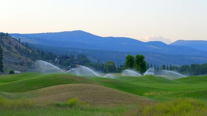 Establishing shot of golf course in service watering with gorgeous green and mountain view in Vancouver, Canada, North America. Day time on May 2022. Still camera. ProRes 422 HQ.