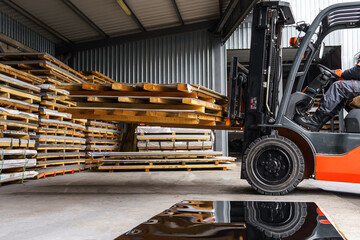Forklift loader in the metal warehouse. Loading and unloading stainless steel sheets