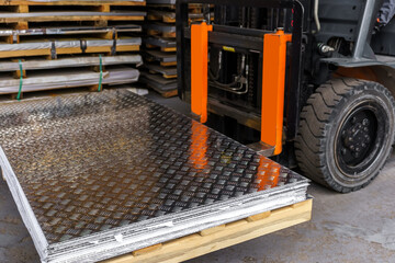 Forklift loader in the metal warehouse. Loading and unloading stainless steel sheets