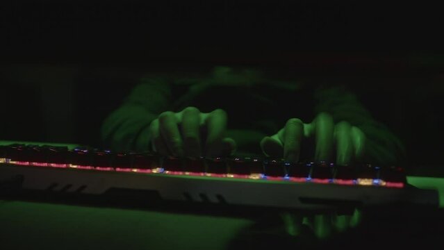 Colorful RGB Keyboard Typing Hacker or Coder Writing Code with Fingers on Green Light