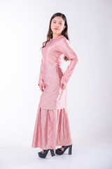 A portrait of a young Indonesian lady looking beautiful wearing traditional Malaysian or Indonesian wear isolated on a white background. Idul Fitri fashion concept.
