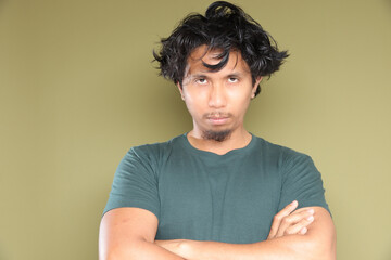 Asian male in messy hair with stress emotion over green background.
