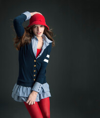 Pretty teen in preppy outfit with red tights holding her cloche hat - 575228930