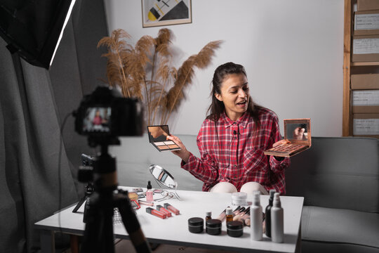 Young Hispanic woman beauty vlogger or blogger recording makeup tutorial to share on social media. Small business selling cosmetics online.