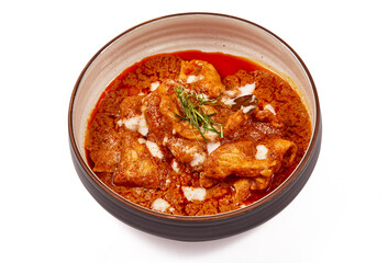 Panang pork curry with coconut milk and sliced kaffir lime leaves in a bowl isolated on white background, Panang curry is a very popular Thai dish.
