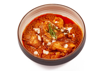 Panang pork curry with coconut milk and sliced kaffir lime leaves in a bowl isolated on white background, Panang curry is a very popular Thai dish.