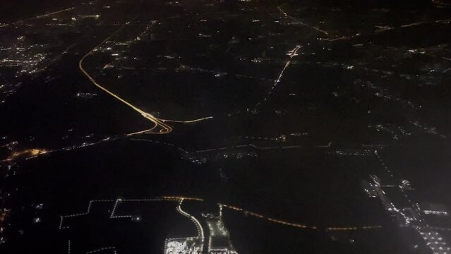 View from airplane wing flying at night over big city