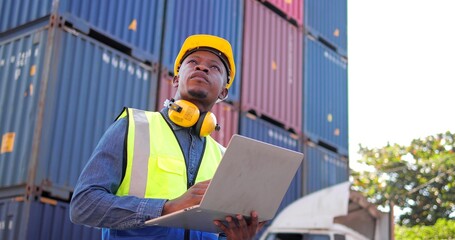 Black African man engineer using laptop control checking container from cargo freight for import...