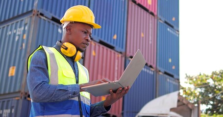 Professional Black African engineer using laptop control checking container at cargo freight for import and export