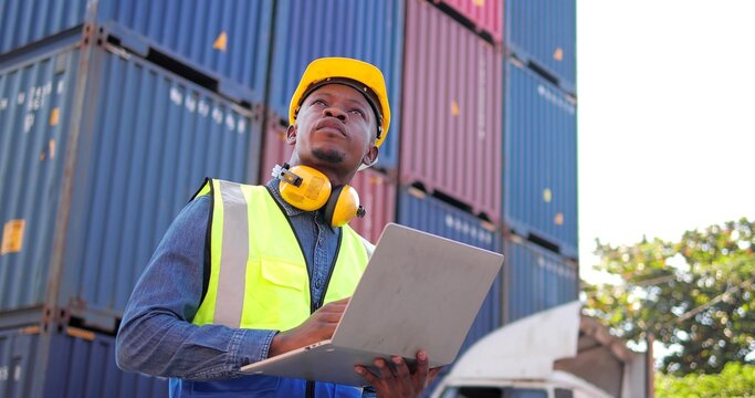 Black African man engineer using laptop control checking container from cargo freight for import and export , support logistics transportation concept