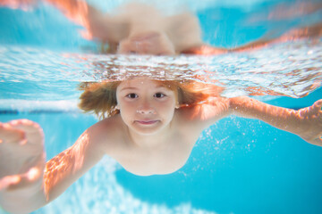 Child swimming underwater in swimming pool. Funny kids boy play and swim in the sea water. Summer...
