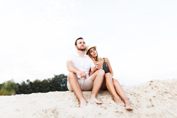 Fototapeta na wymiar young couple in love are sitting on a sandy beach on vacation