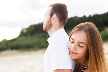 Obraz premium man and a woman are hugging on a sandy beach in summer