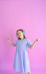 Pretty little girl wearing a purple dress and headphones while dancing to music. 