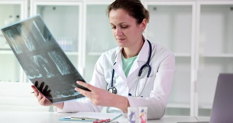 Female doctor examines x-ray of a patient spine during visit