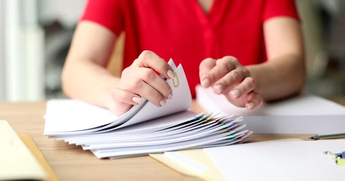 Hands of businesswoman look over stack of documents on office table
