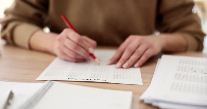 Student hold red pencil and write their chosen answer