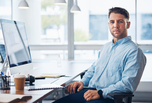 Businessman, Portrait And Serious Financial Advisor By Computer With Documents In Sales Sitting By Office Desk. Corporate Male Employee By Desktop PC On Chair Ready For Finance Advice, Loan Or Help