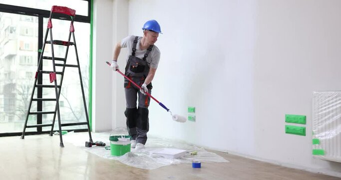 House painter paints wall of apartment with roller brush