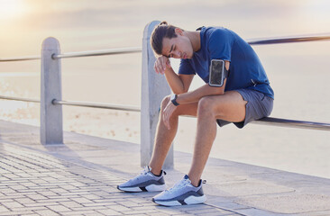 Tired runner man, sitting and beach for workout, health and exercise with headache, rest and relax....
