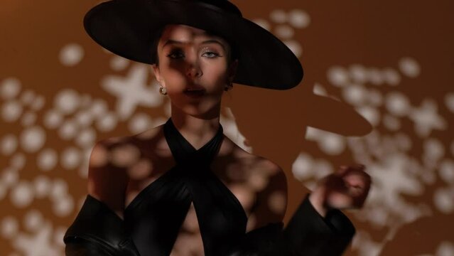 Fashion portrait of a girl in the studio with a black hat with golden decorations. Jewelry.