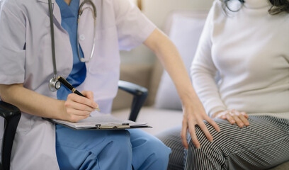 Obraz premium Female doctor in white medical coat discussing elderly patient in clinic, therapist. Consulting woman examining knee pain, health care, medicine concept.
