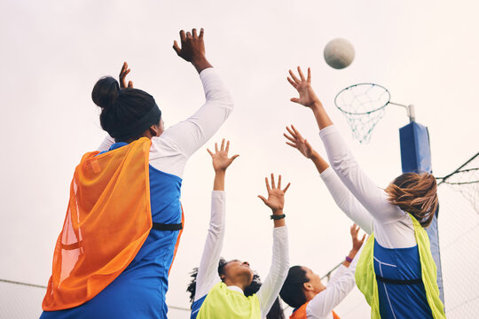 Netball, goal shooting and fitness of a girl athlete group on an outdoor sports court. Aim, sport game and match challenge of a black person with a ball doing exercise and training in a competition
