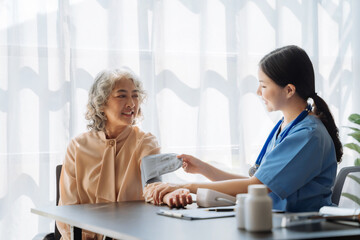 Fototapeta premium Female doctor having blood pressure test elderly woman at the clinic in the morning.