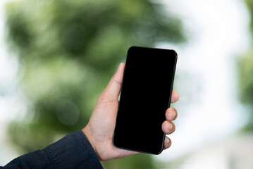 Man holding smartphone screen, close-up of hands. Space for text and blur inside abstract green background with natural.